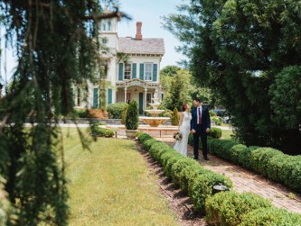 Bride and groom holding hands and walking down the path by the fountain